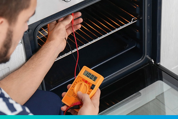 Techniker hält Messgerät in einen Backofen