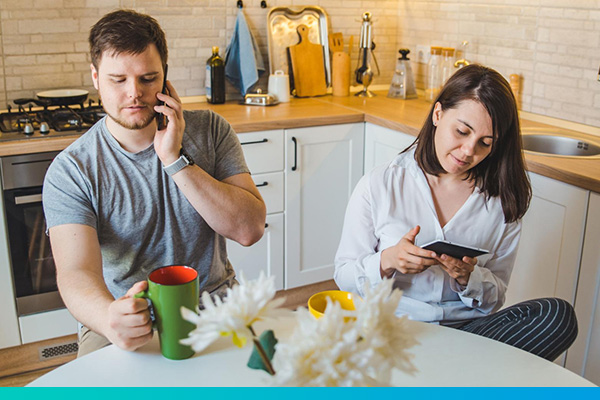 Paar am Küchentisch, Mann telefoniert