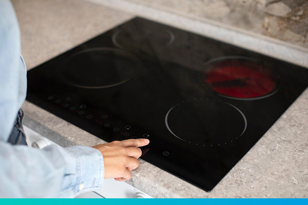 Eine Hand regelt einen Elektroherd