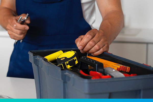 Werkzeugkasten im Vordergrund, im Hintergrund unscharf Techniker mit Schraubenschlüssel in der Hand