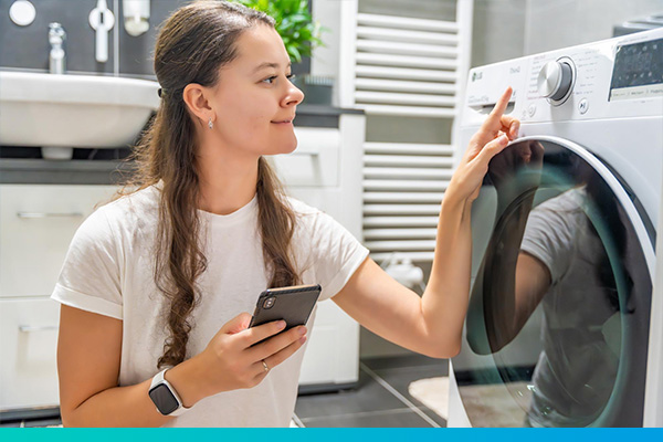 Frau am Telefon vor einer Waschmaschine