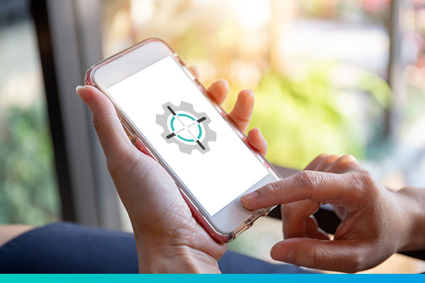 Hand hält eine Handy in der Hand und tippt darauf. Auf dem Display ist das Taktik Reparatur Logo