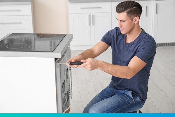 Techniker schraubt an der Rückseite eines Backofen