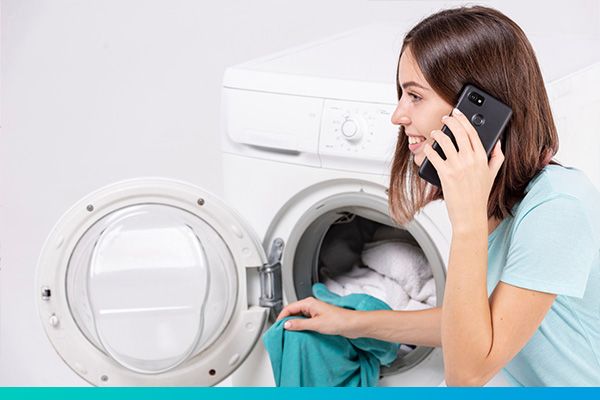 Frau telefoniert vor einer Waschmaschine